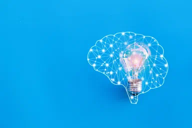 A lightbulb representing an idea surrounded by a network in the form of a brain.