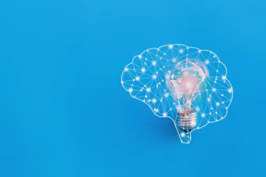 A lightbulb representing an idea surrounded by a network in the form of a brain.
